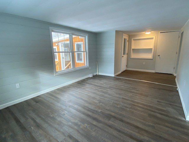 Empty room with gray wood floors, light blue walls, and a window.