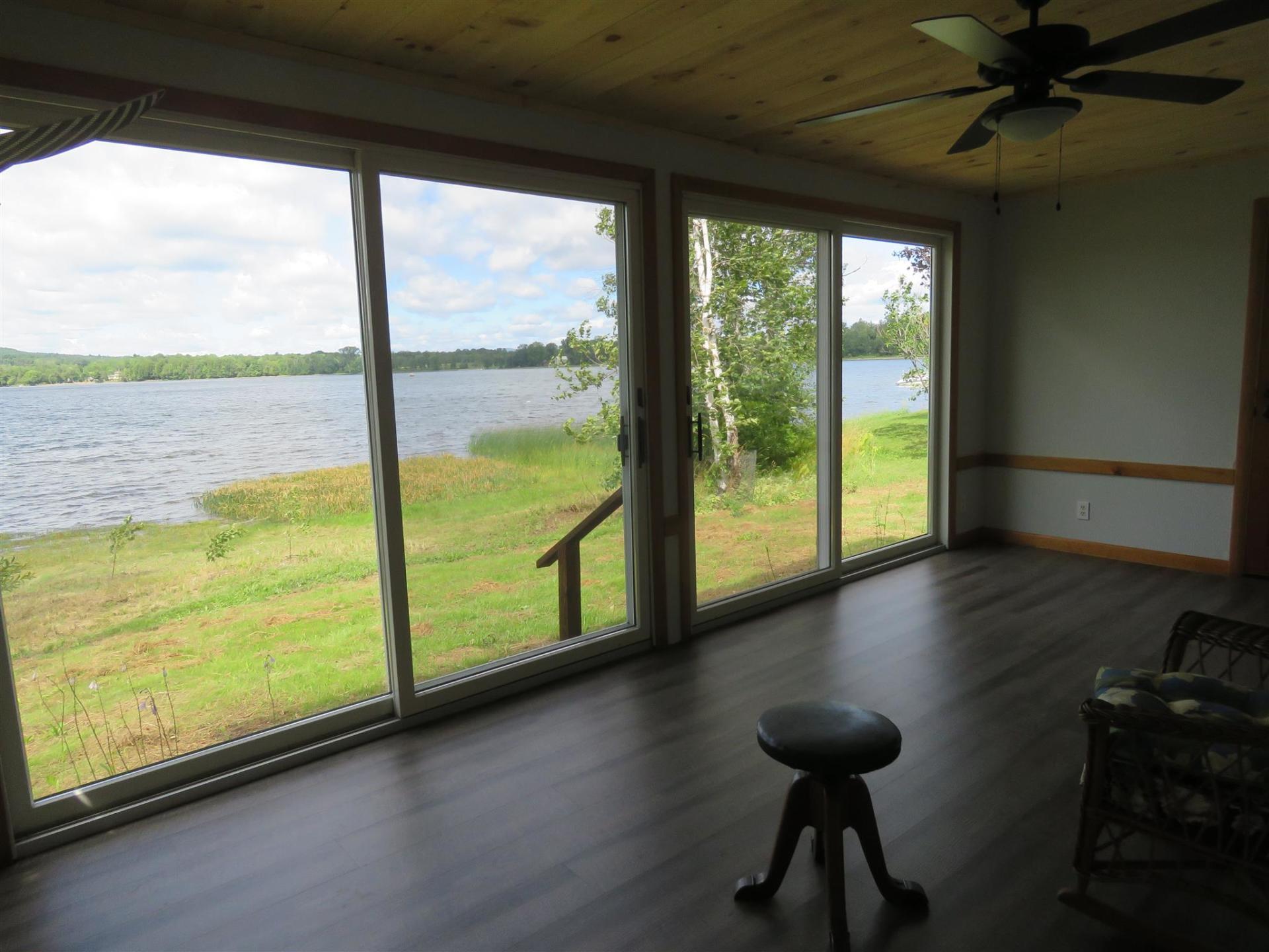 A room with a view of a lake and a ceiling fan