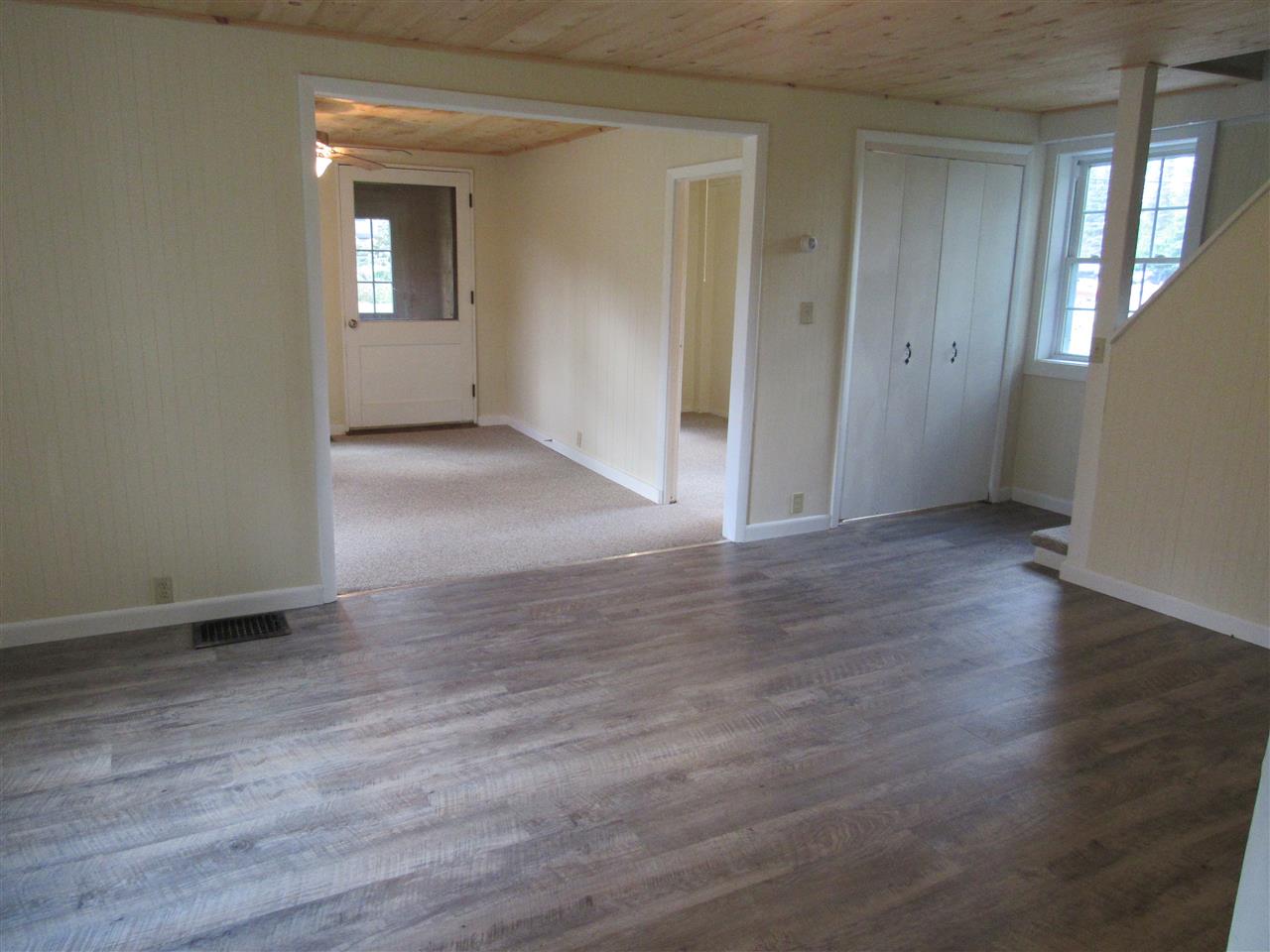 Empty interior room with hardwood floors, doorways, and a closet.