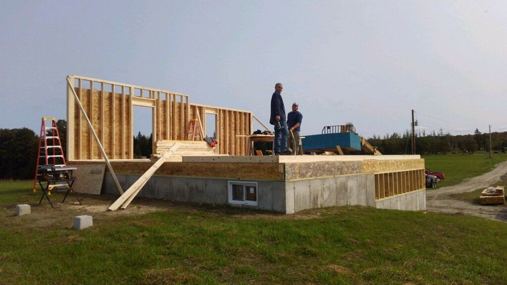 Two men are standing in front of a house under construction