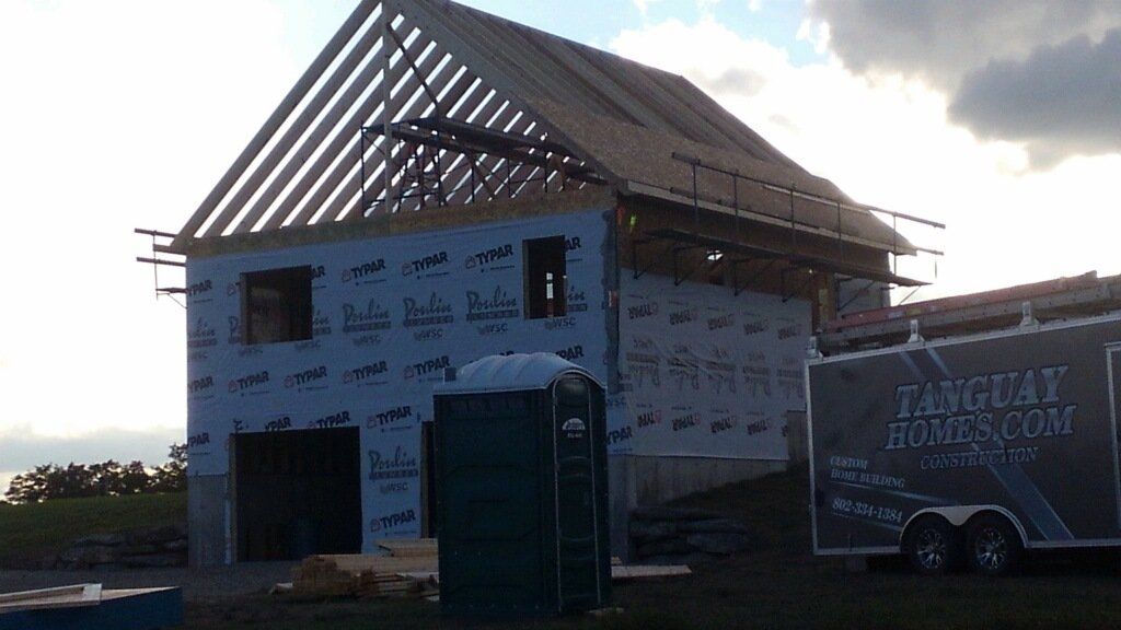 A tanguay moving company truck is parked in front of a house under construction