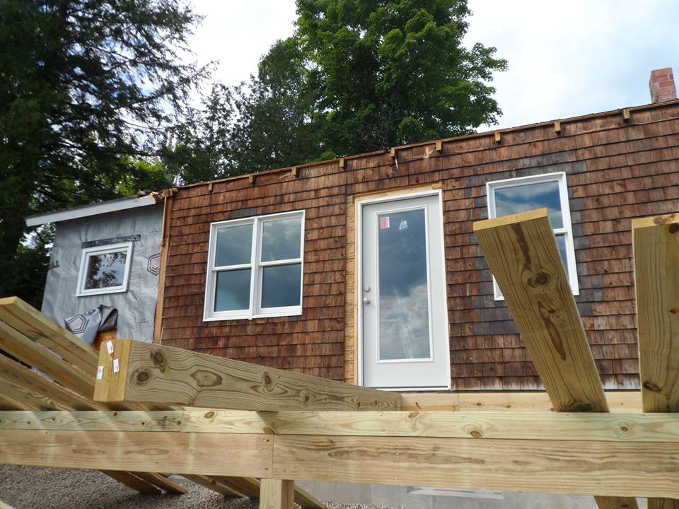Partially built wooden deck in front of a brick house with a white door and windows