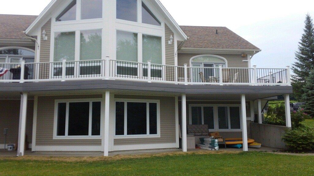 Two-story house with large windows, deck, and a grassy backyard