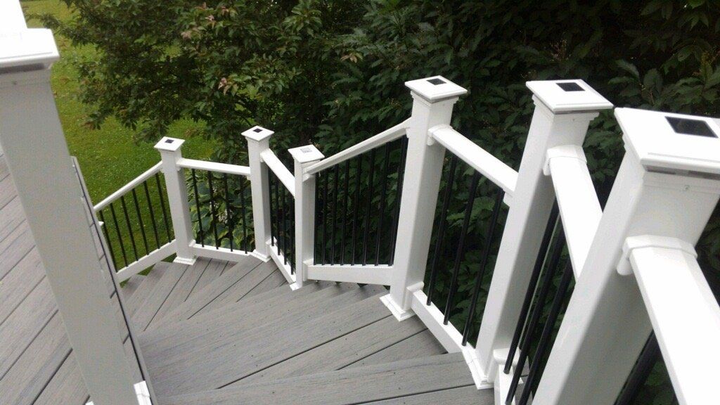White-railed wooden staircase descending to a green yard with black balusters