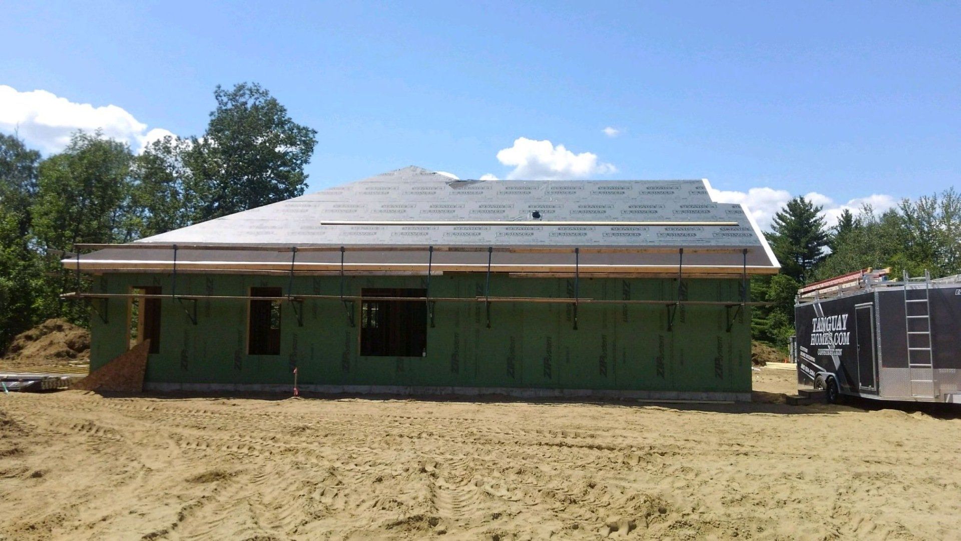 A roof is being installed on a house under construction