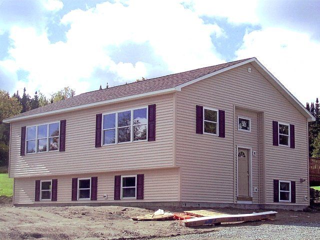 New beige two-story house under construction with unfinished yard and siding, front view