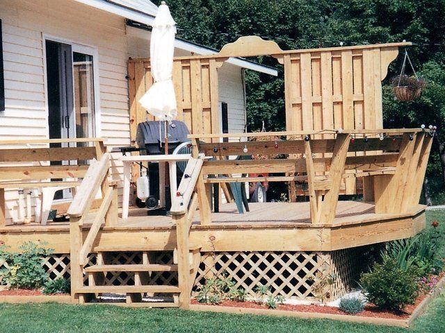 Wooden backyard deck under construction beside a house, with railing and steps in progress