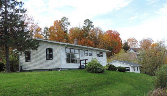 Sell Your Home Fast and Hassle-Free A white house sits on top of a grassy hill surrounded by trees