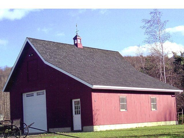 A red barn with a white door and a black roof