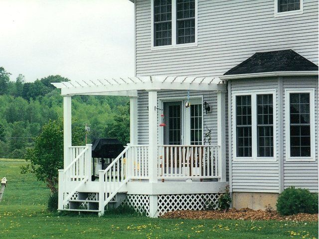 White house porch with pergola, lattice skirting, and sliding glass doors overlooking a green yard