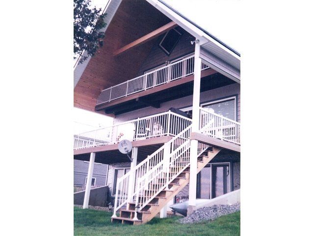 Exterior staircase on a house with white railings and a covered balcony underneath