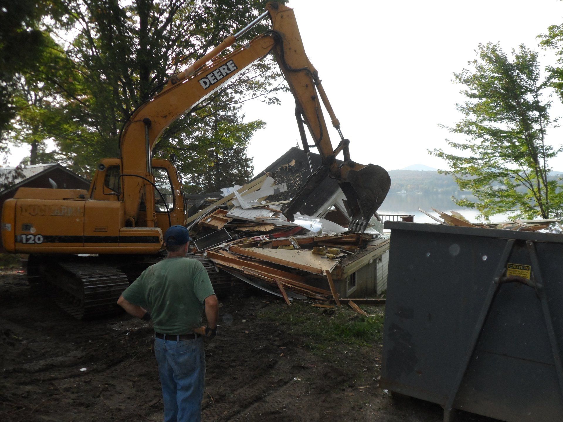 A man stands in front of a deere excavator