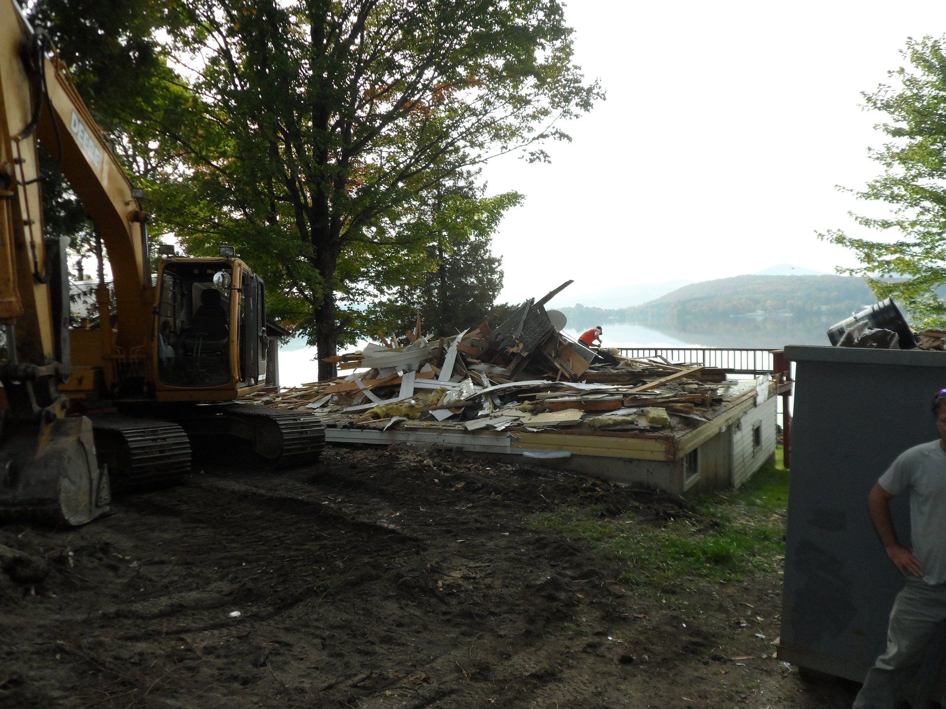 A large yellow excavator is demolishing a house