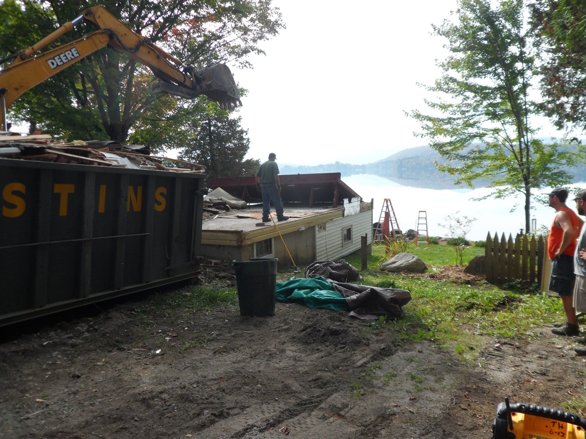 A dumpster with the word stins on it is being filled with rubble