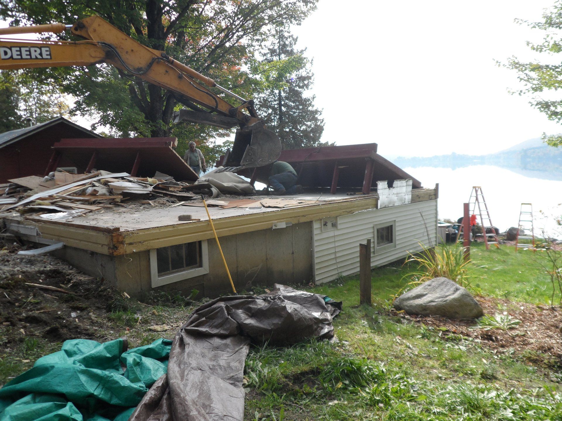 A house is being demolished by a john deere excavator