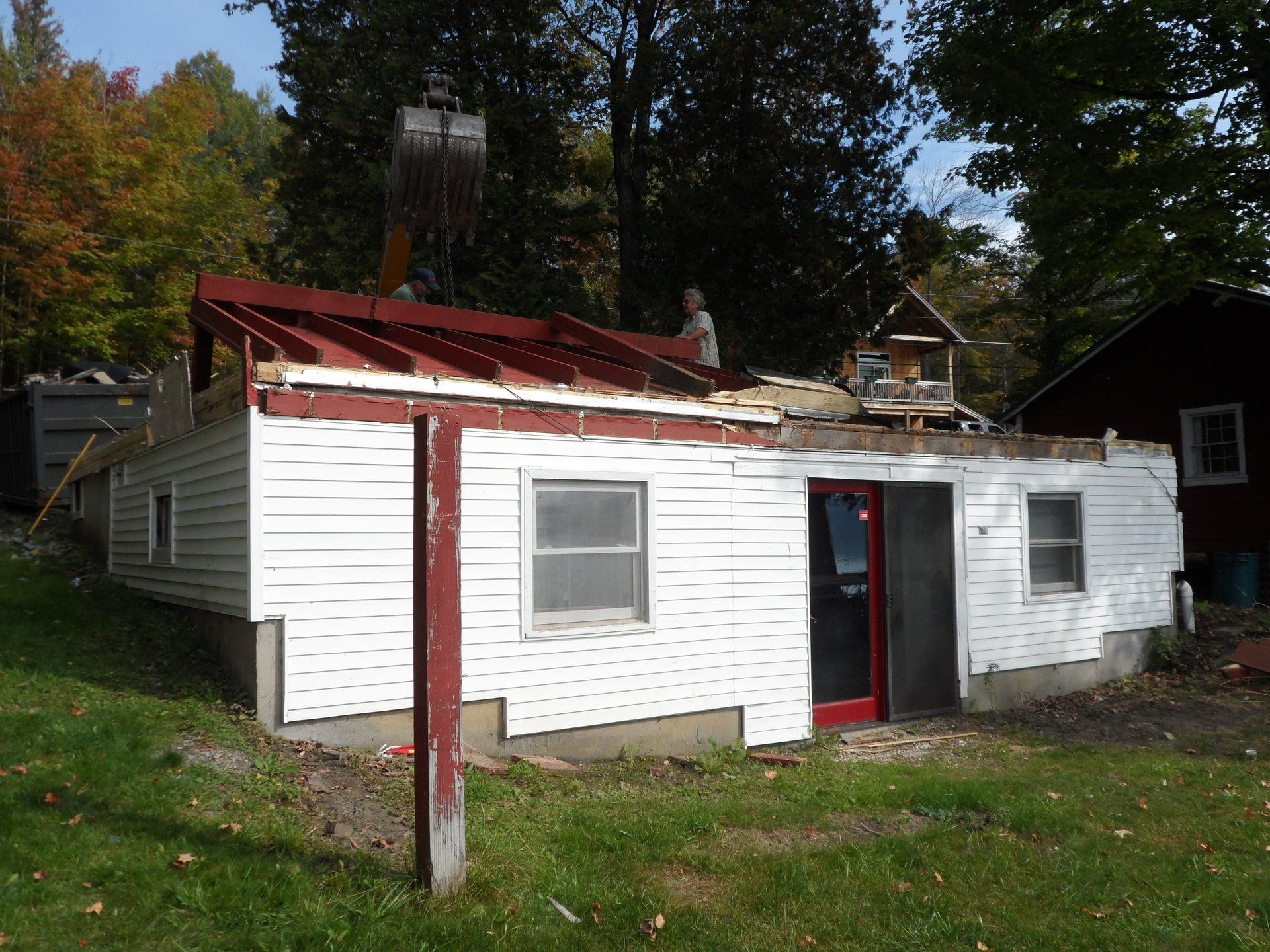 A white house with a red door is being demolished