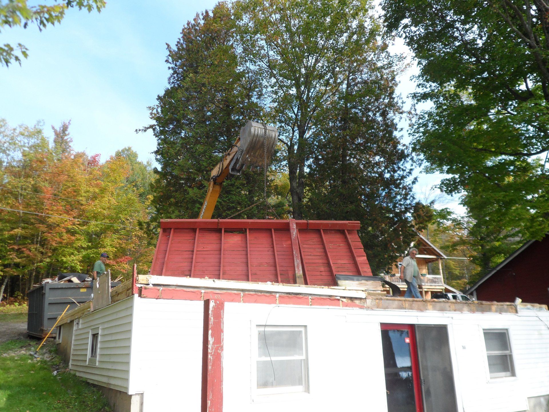 A white house with a red roof is being demolished