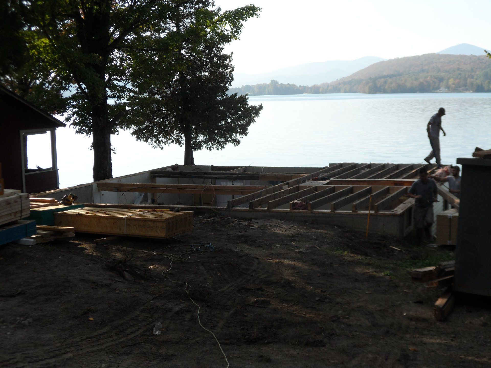 A man standing on top of a pile of wood next to a body of water