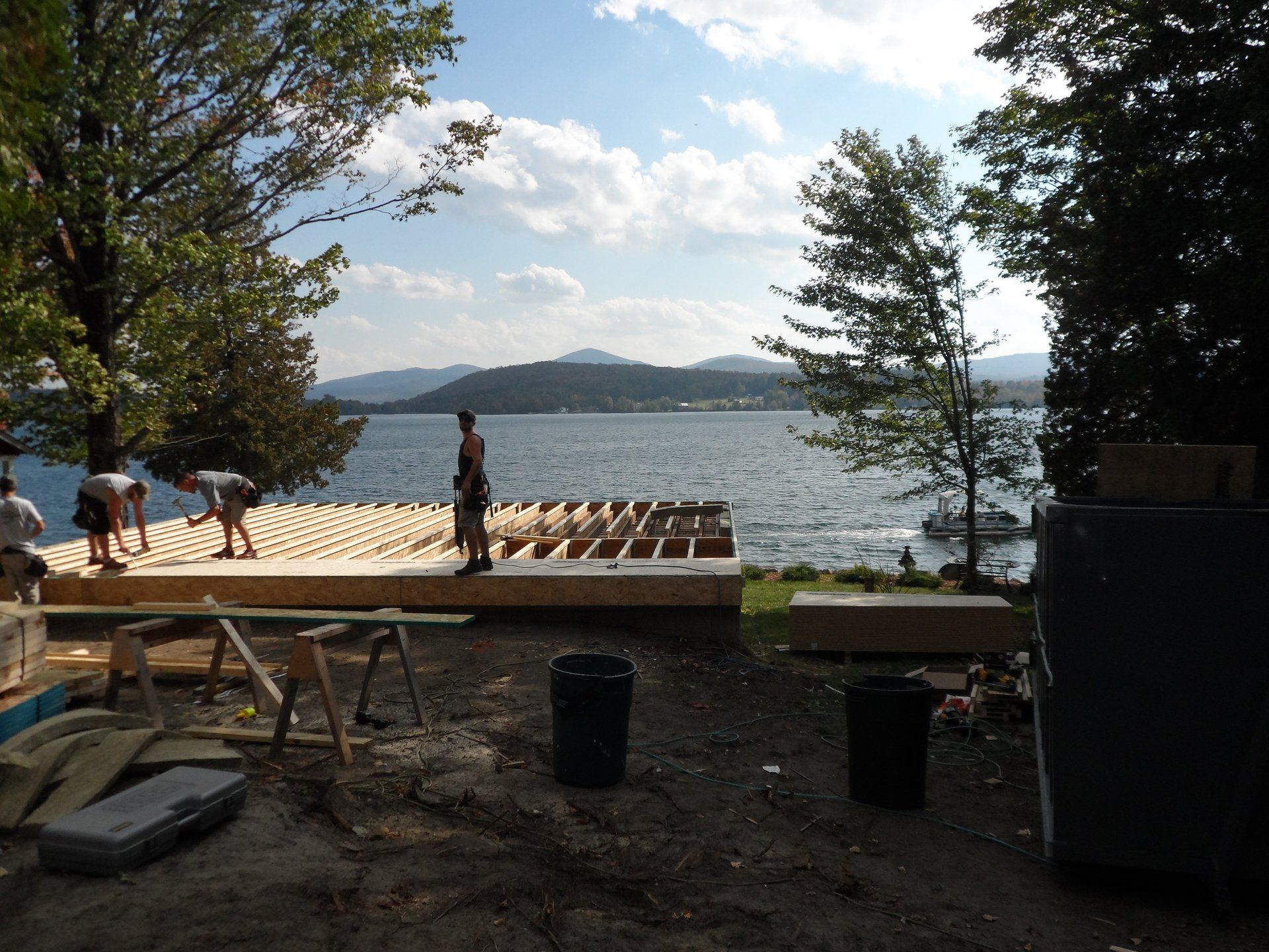 A group of people are working on a deck overlooking a lake