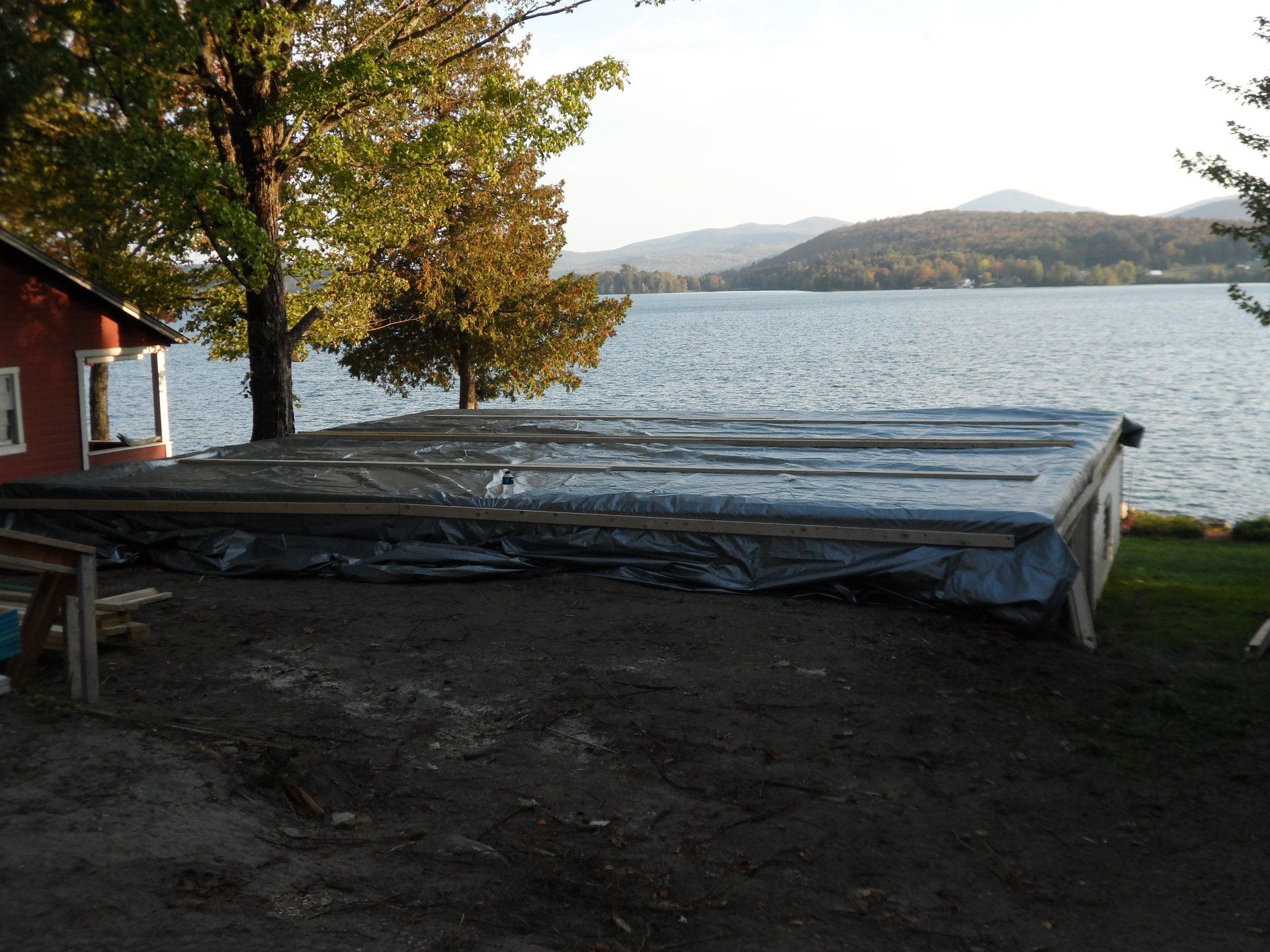 A large tarp is sitting on the ground in front of a lake