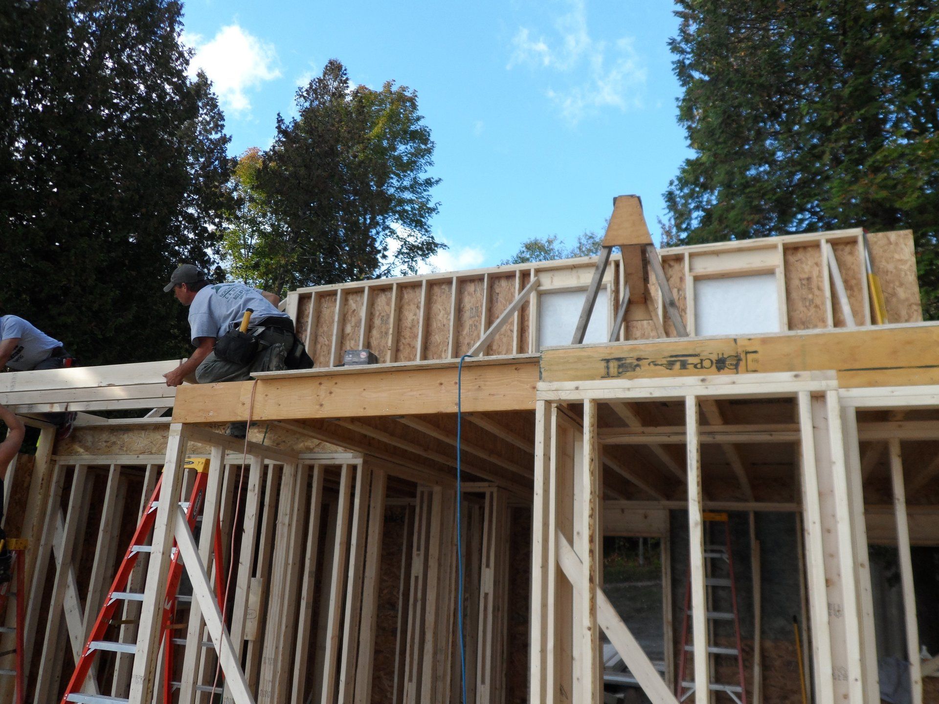 Two men are working on the roof of a house that is being built