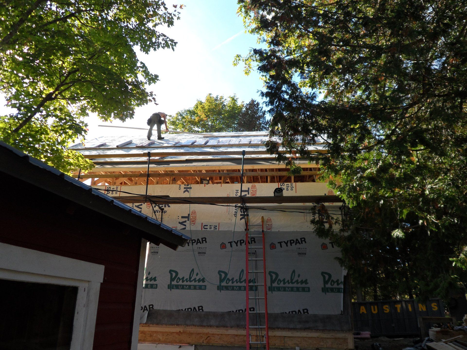A man is working on the roof of a house with a ladder