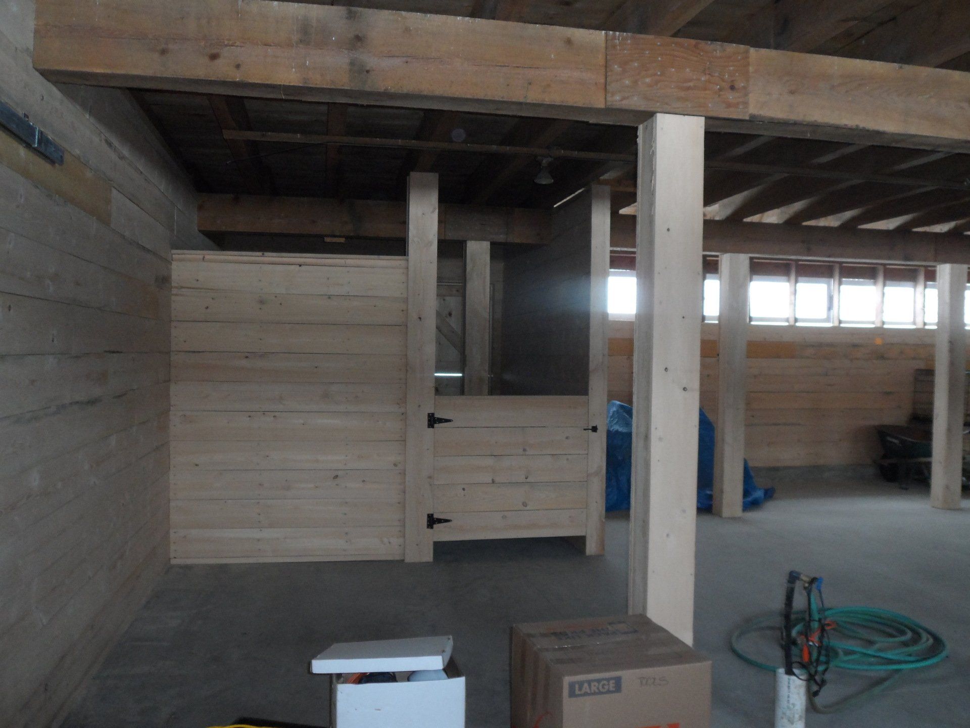 Wooden stall under construction in a large, open barn.