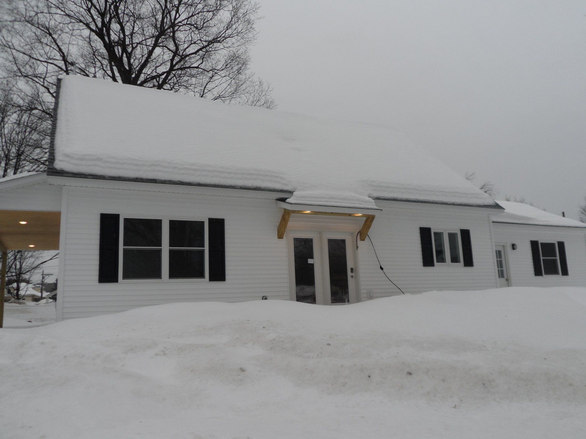 A white house with black shutters is covered in snow