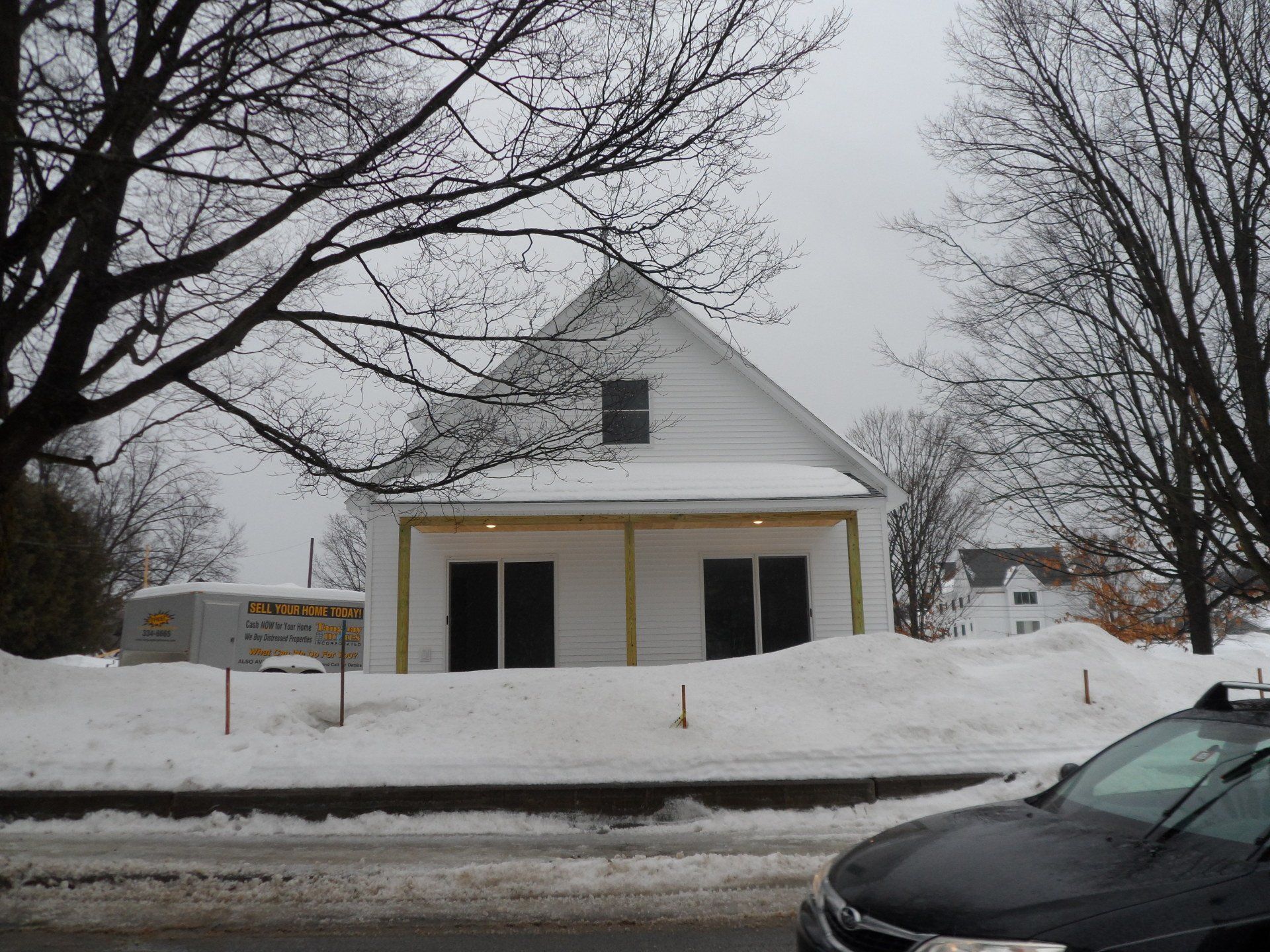 A black car is parked in front of a snow covered building