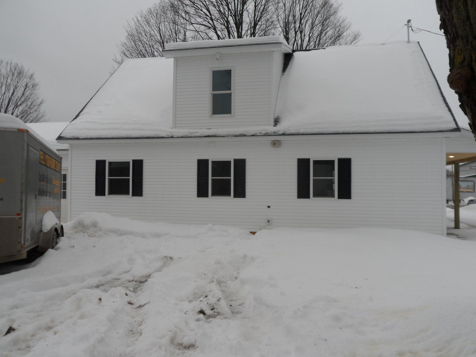 A white house with black shutters is covered in snow