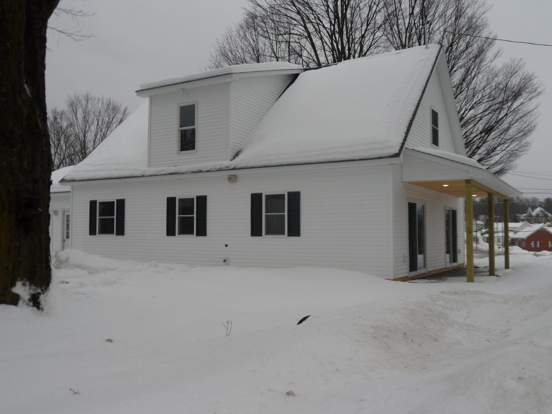 A white house with black shutters is covered in snow