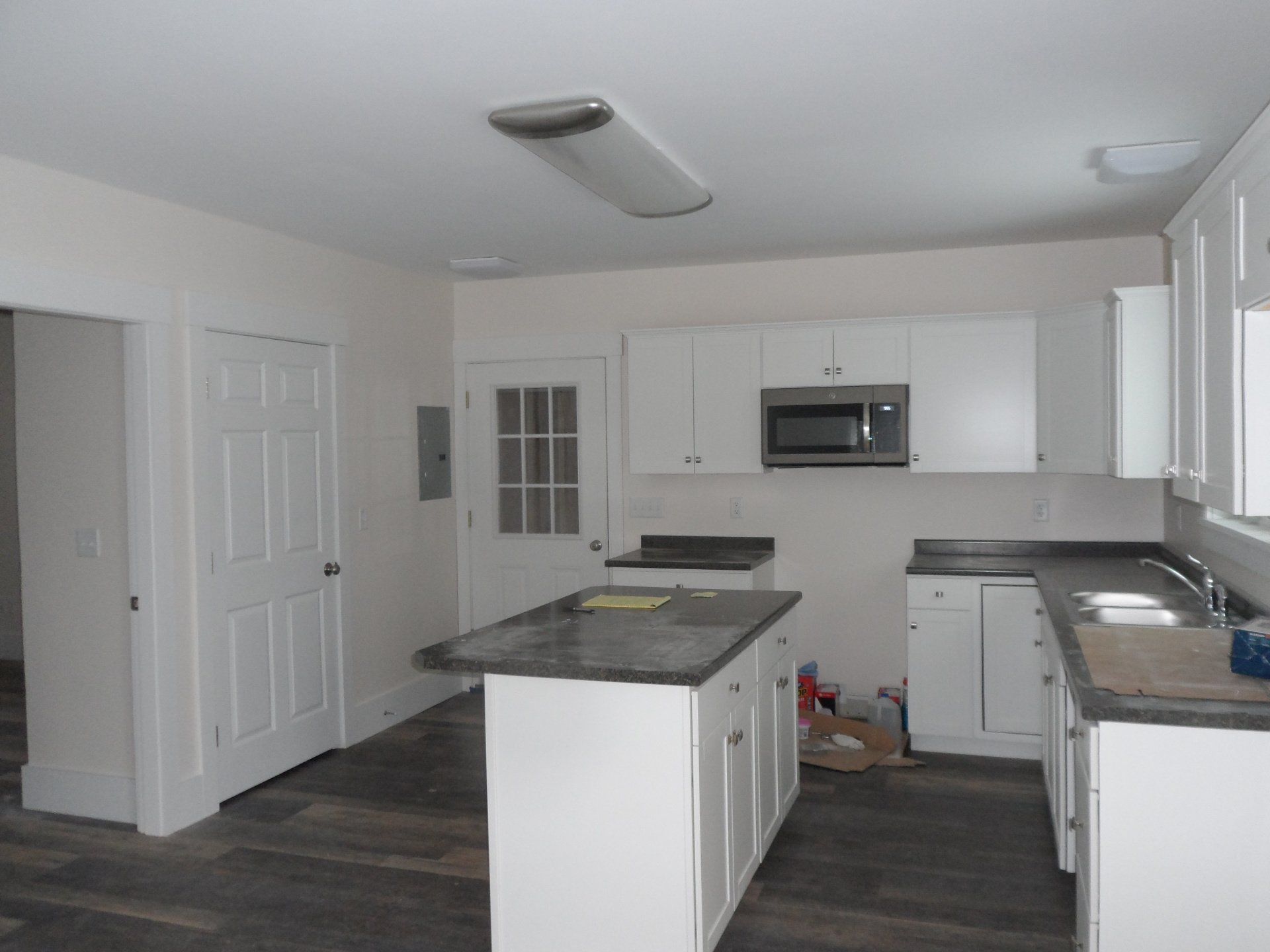 An empty kitchen with white cabinets and a microwave