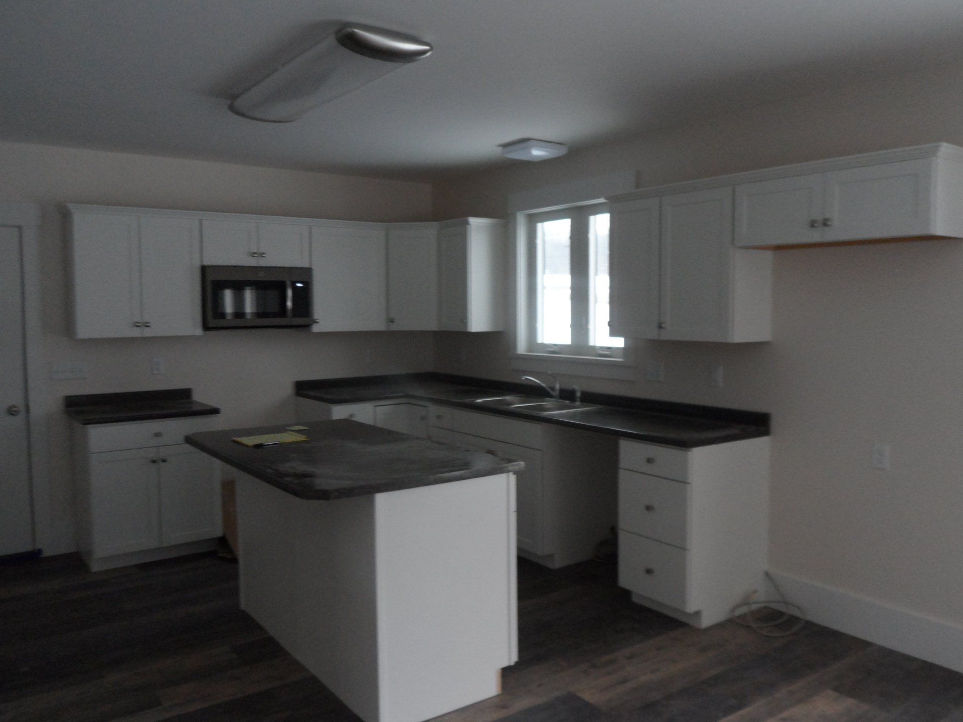 A kitchen with white cabinets and black counter tops