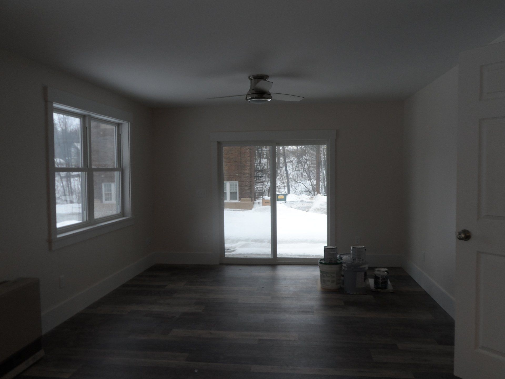 An empty room with a sliding glass door and a ceiling fan