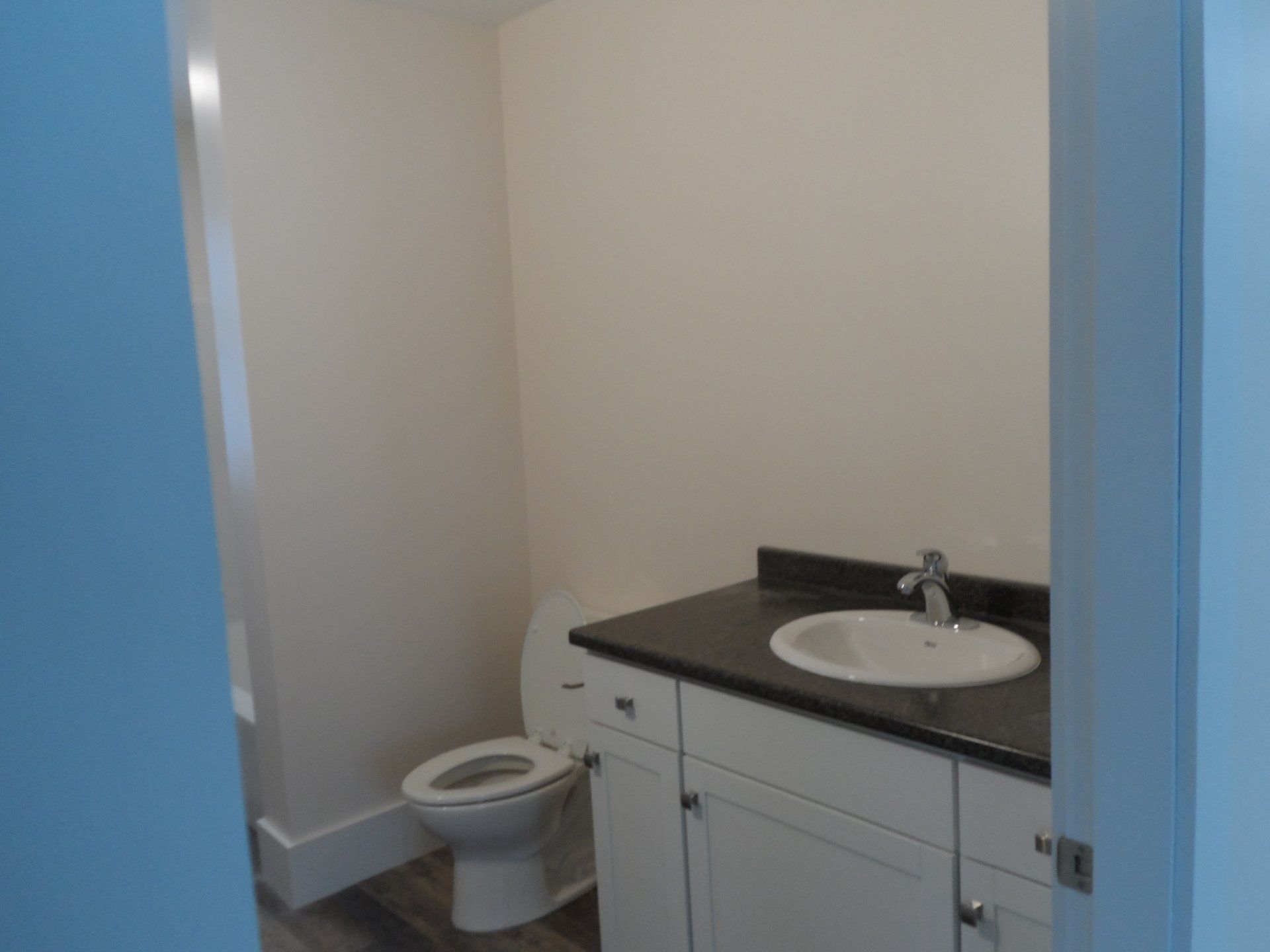 A bathroom with a toilet , sink and cabinets.