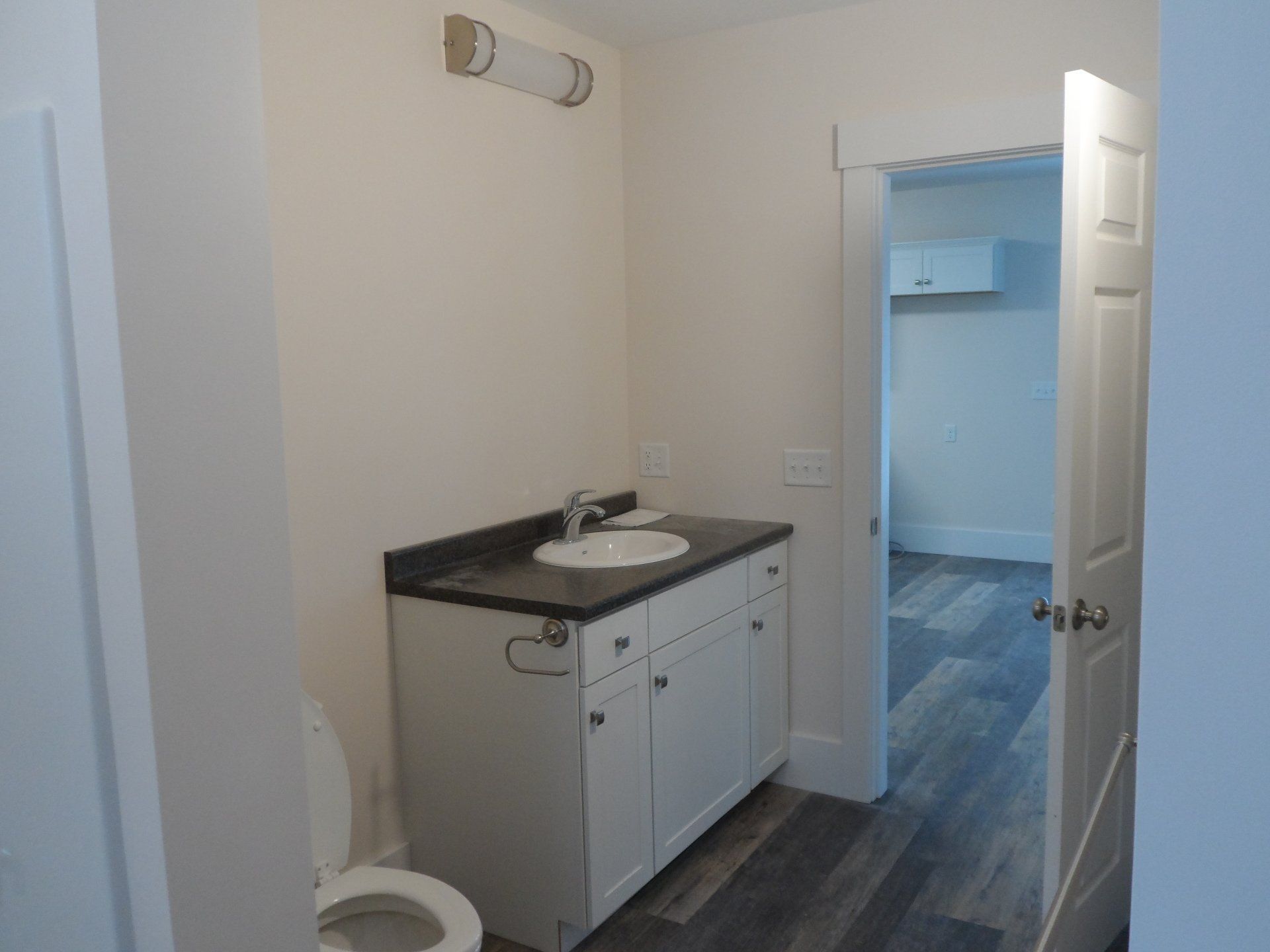 A bathroom with a toilet a sink and a light on the wall