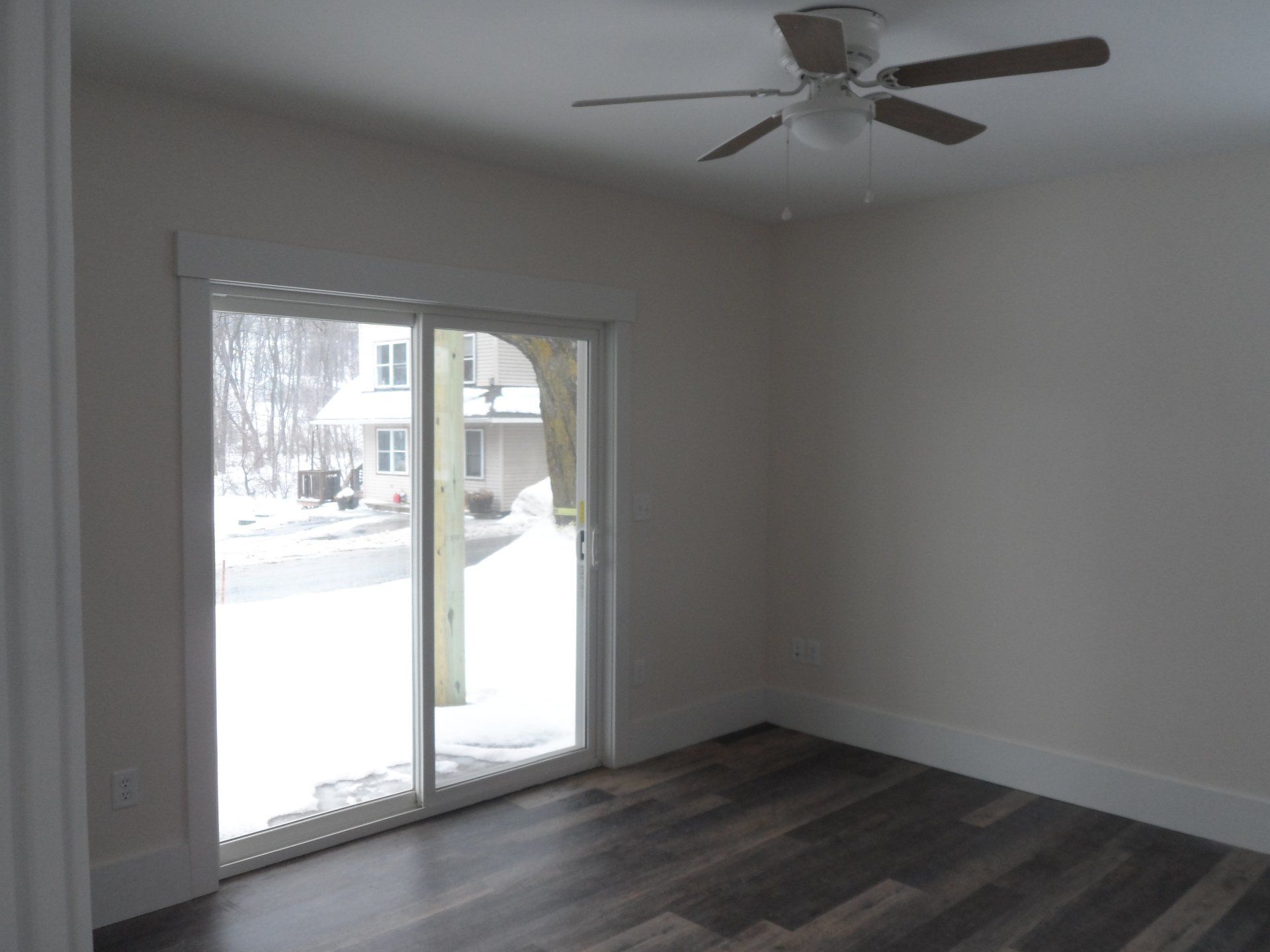 An empty room with a ceiling fan and a sliding glass door