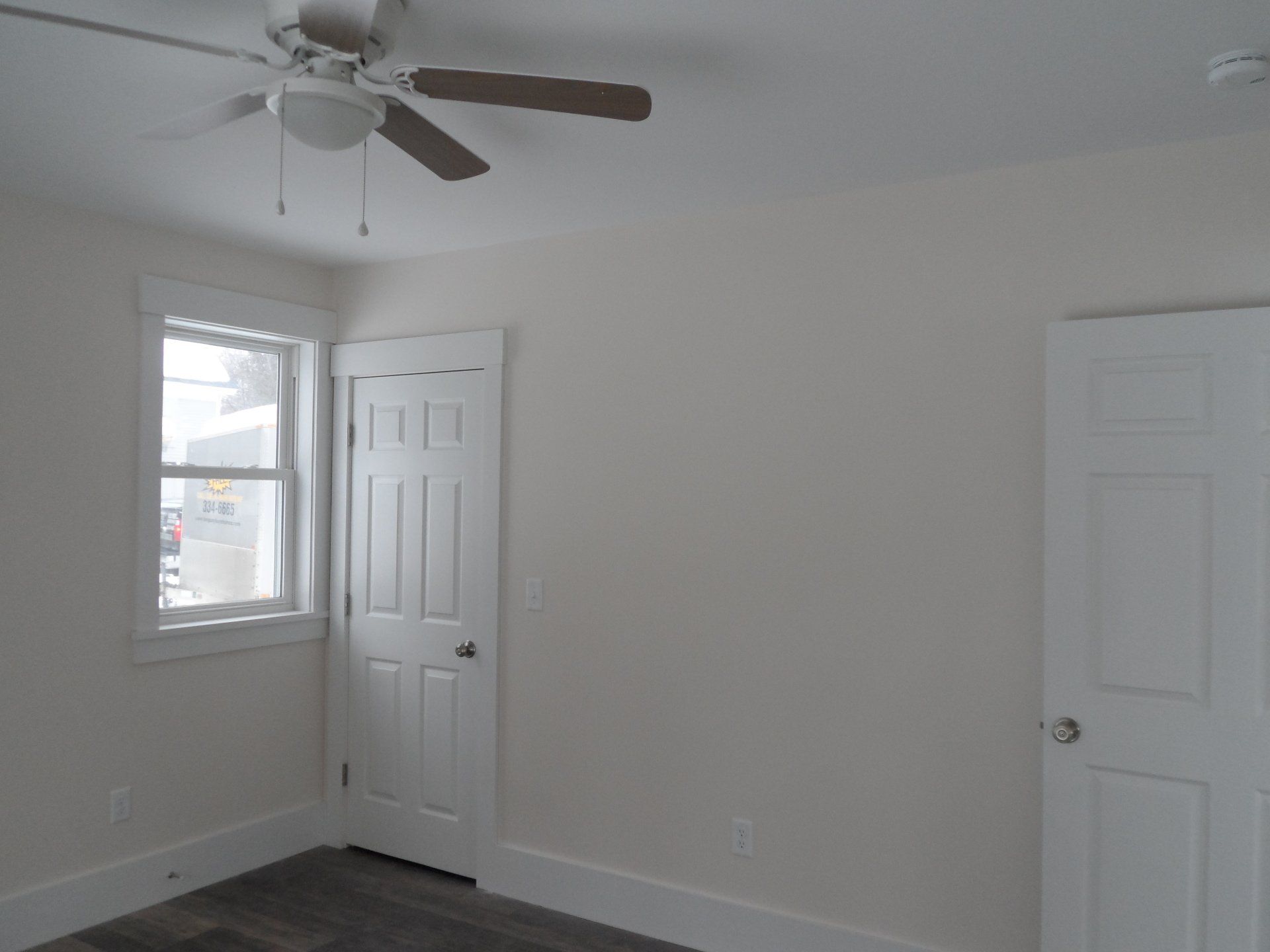 An empty room with a ceiling fan and a window
