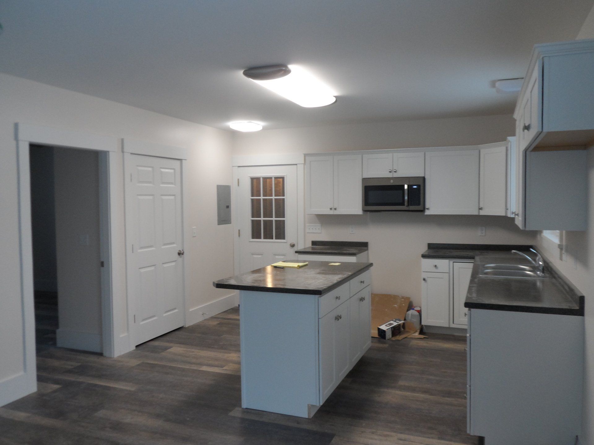 A kitchen with white cabinets and black counter tops