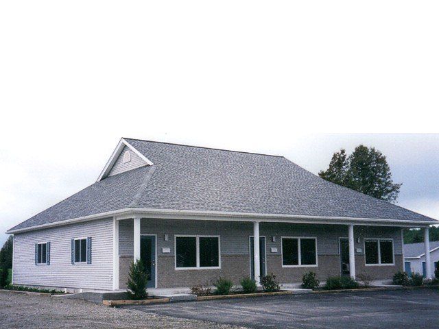 Gray house with a large gabled roof and covered front porch on a cloudy day