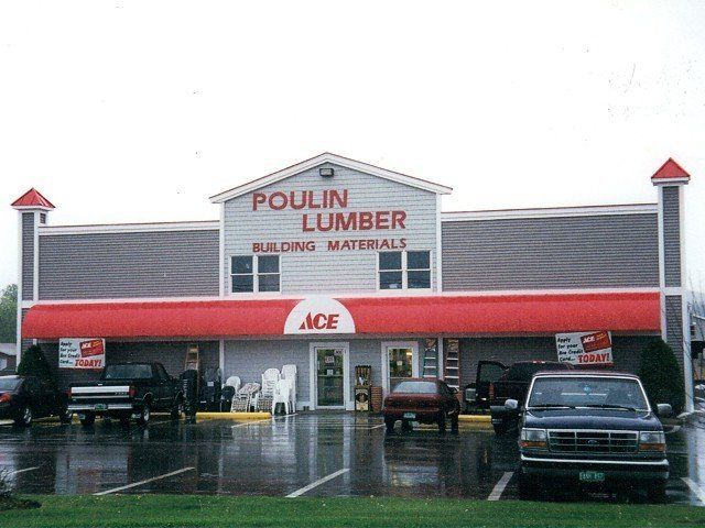 Ace hardware store with red awning and parked cars in front on a rainy day