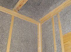 Interior of a wooden frame construction filled with gray insulation.