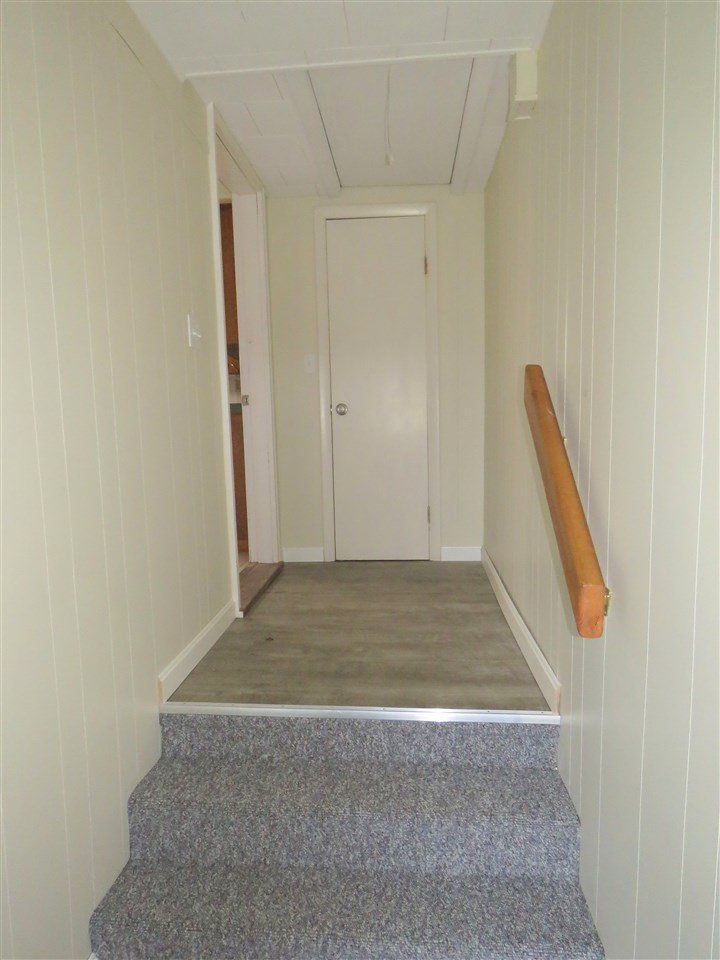 Staircase with gray carpet leading to a hallway with a closed white door and light walls.