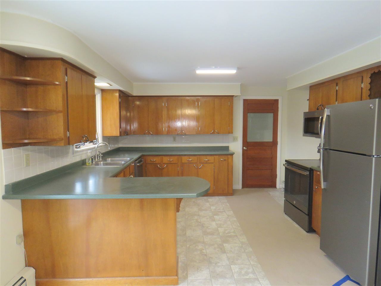 Kitchen with wood cabinets, green countertops, and black appliances.
