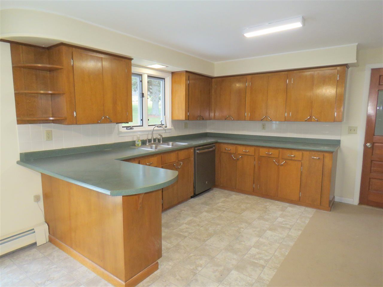 Kitchen with wooden cabinets, green countertop, and a stainless steel dishwasher.