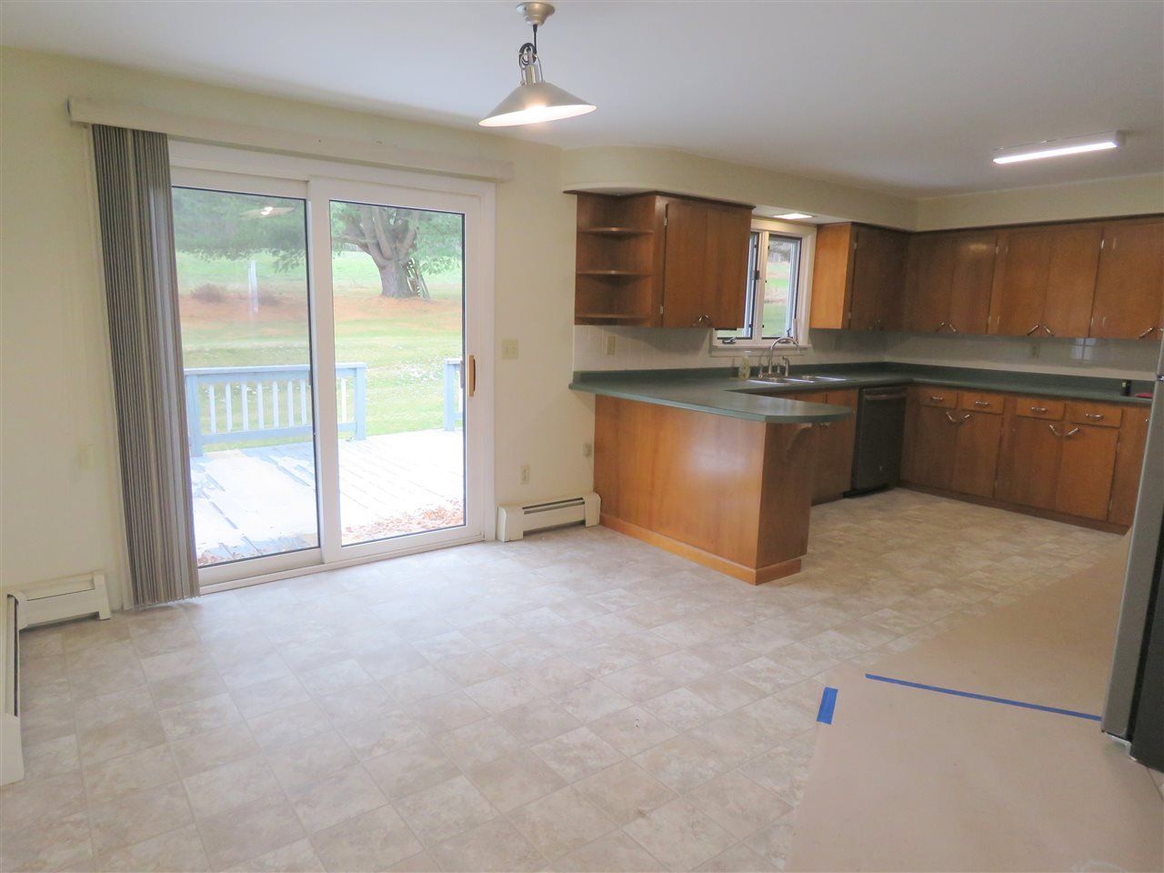 Kitchen with wood cabinets, light-colored countertops, and sliding glass door to a deck. Light carpet.