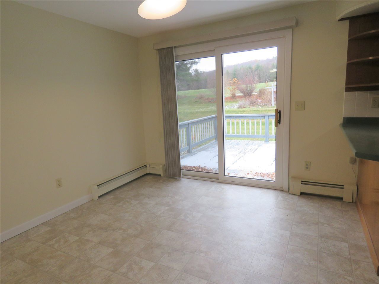 Empty room with sliding glass door leading to a deck. Beige walls and flooring.