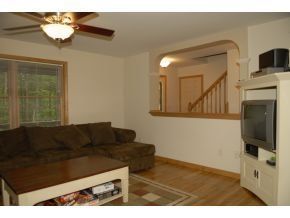 A living room featuring a brown sectional sofa, a wooden coffee table, a ceiling fan, and a built-in media center.