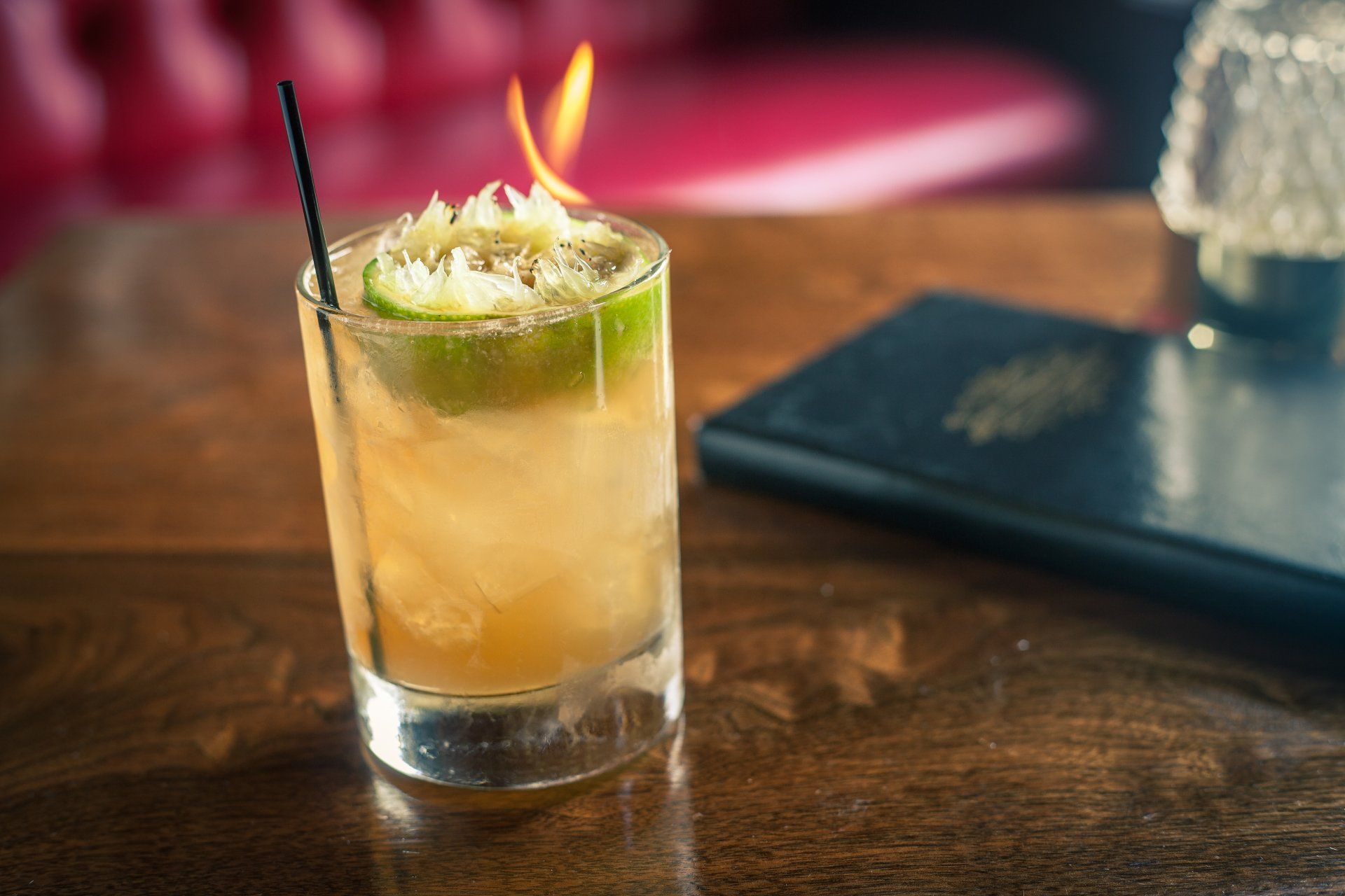 cocktail on bar top with a lime topper on fire at planter's house st. louis
