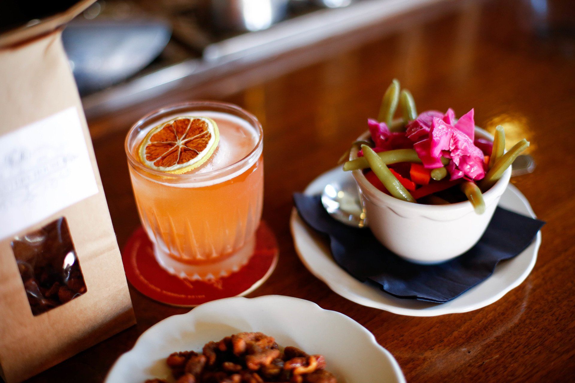 handcrafted cocktail on bar top with a side of pickled veggies at planter's house st. louis
